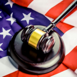 Wooden judge's gavel resting on an American flag, symbolising the US legal system, courts, justice, and constitutional law.