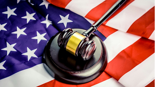 Wooden judge's gavel resting on an American flag, symbolising the US legal system, courts, justice, and constitutional law.